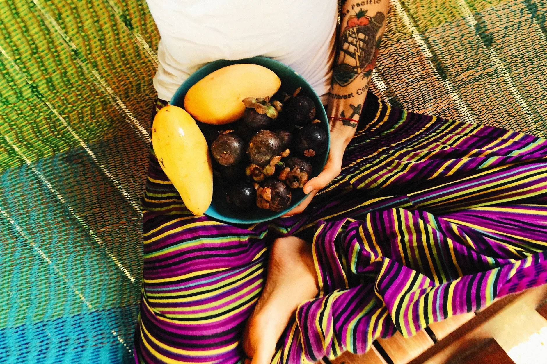 Colorful scene with mangos and mangosteens on vibrant striped clothing.